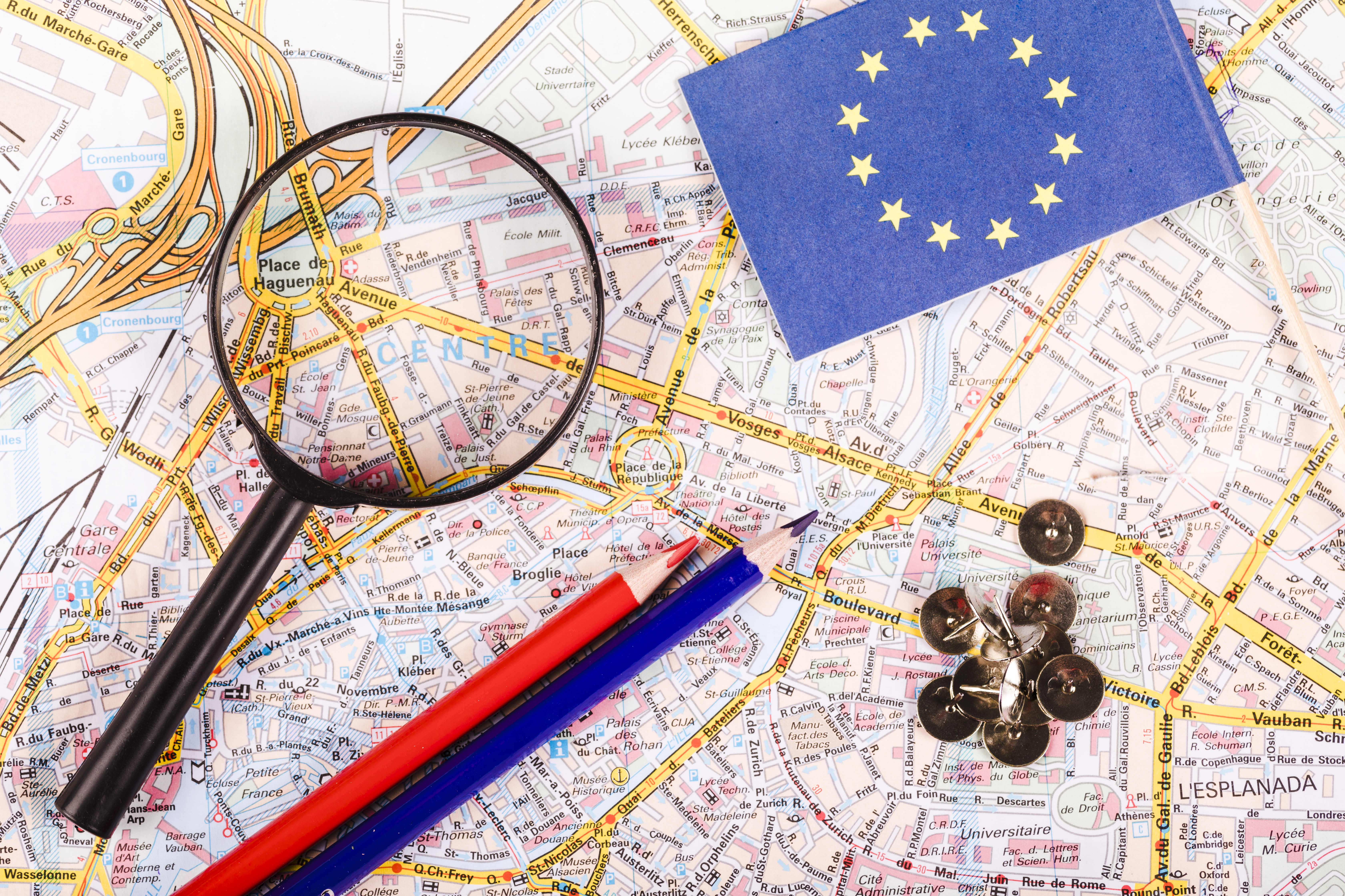 elevated-view-magnifying-glass-pushpins-pencils-flag-map.jpg